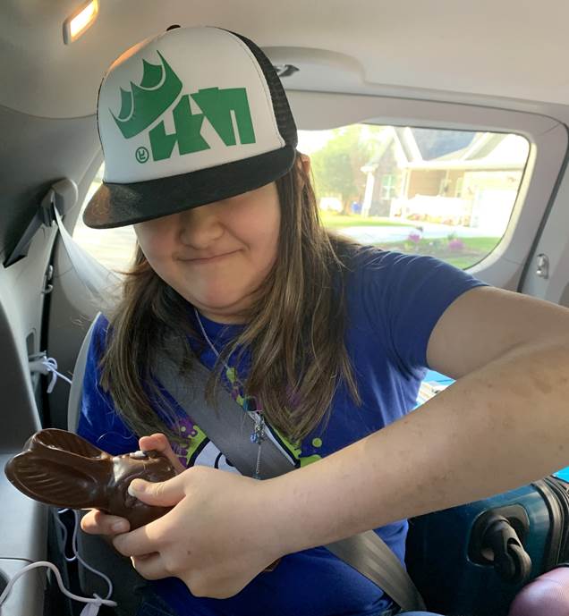 A child in a car eating a chocolate bunny

Description automatically generated with low confidence